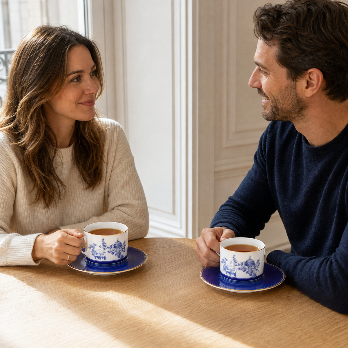 Two people enjoying tea with Golden Harmony cups and saucers